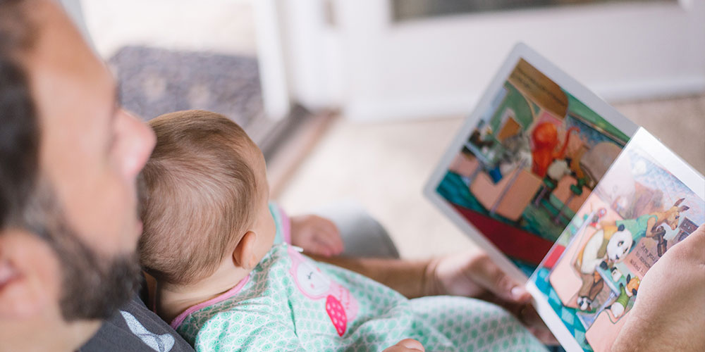 Man holding a baby reading a children's story